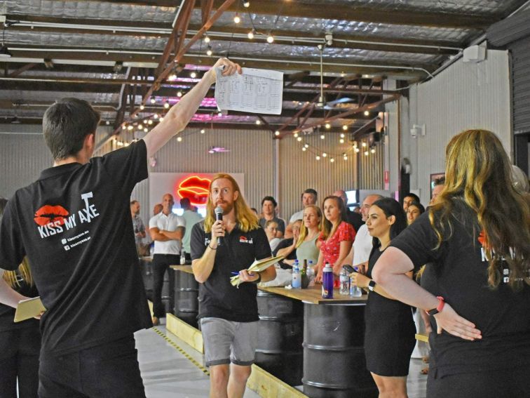 man holding microphone at axe throwing venue