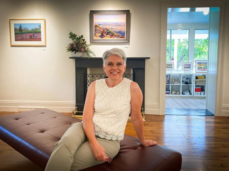 Artist Therese Crow, sitting in her gallery with a smile .