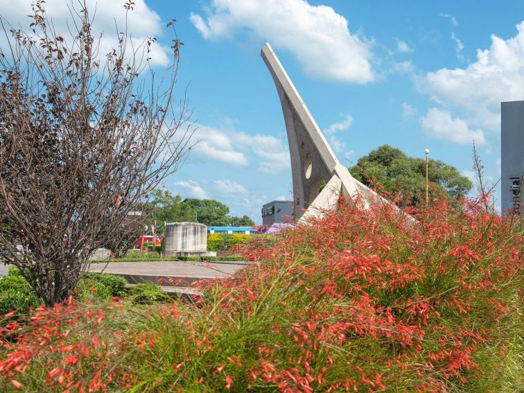 Singleton Sundial as seen through flowering plants in Rose Point Park.