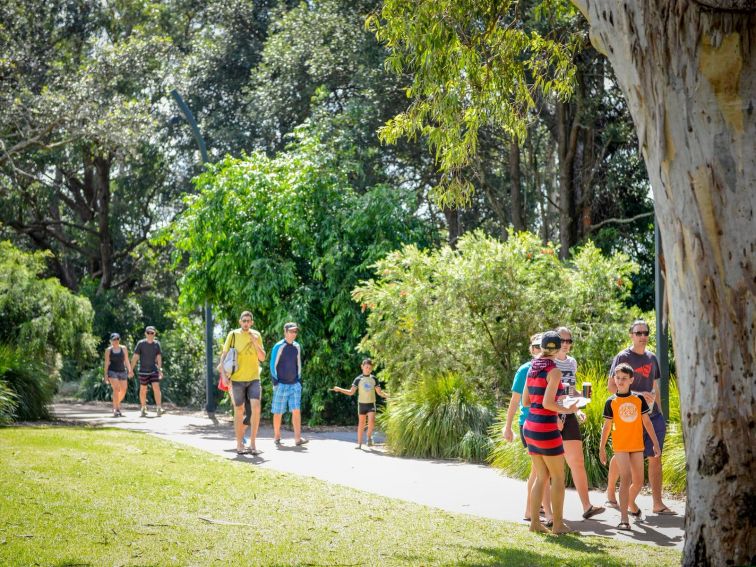 Families walking along the track of the white sands walk, surrounded by trees