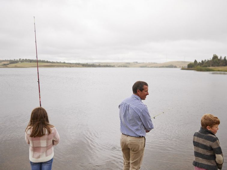 Young girl, adult male and boy standing on the edge of Pejar Dam