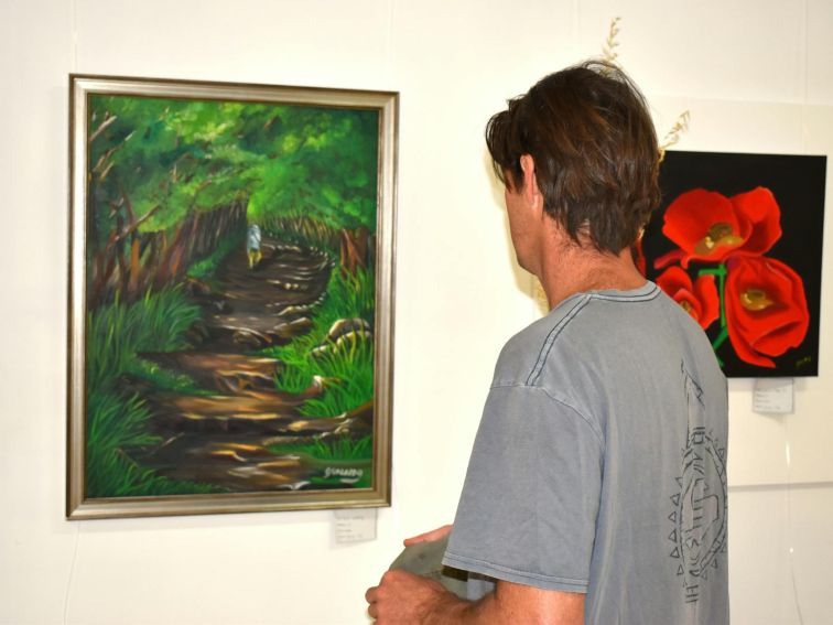Visitor looking at art work depicting a path through the forest.