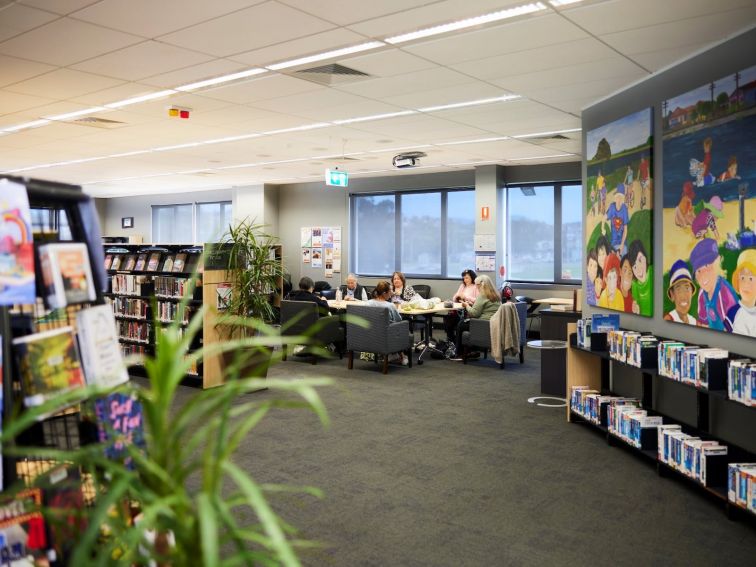 A group of people sitting around a table at Warrawong Library, talking and knitting.