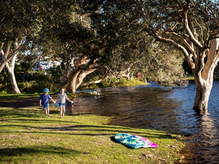 Kids running along banks of Lake Ainsworth