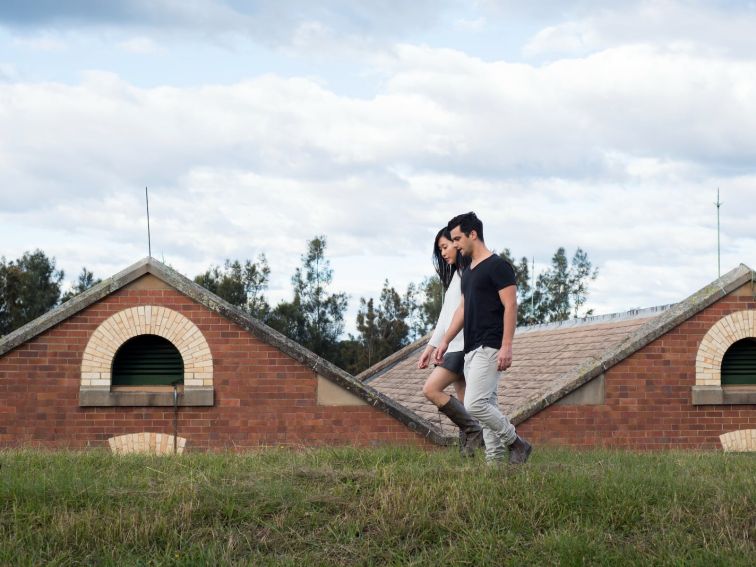 Two people walking in foreground of a heritage red brick building with gable roofline.