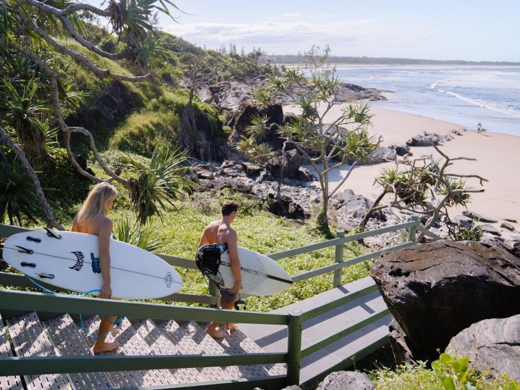 couple taking surf boards down to Cabarita Beach