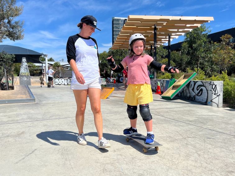 A beginner student guided by her skate instructor whilst learning how to push.