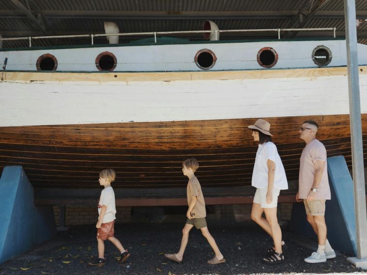 family walking alongside a timber boat