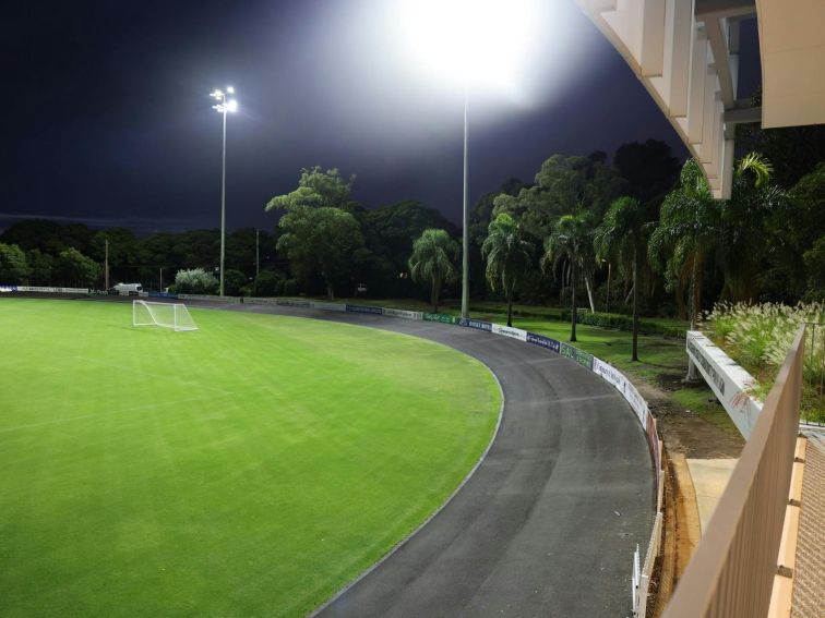 A photo of Hurstville Oval at night with the field lights lit on the field