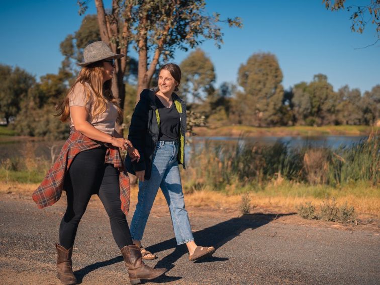 two girls walking next to a body of water