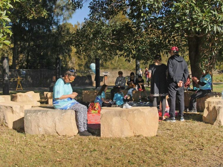 People seated around yarning circle of sandstone blocks.