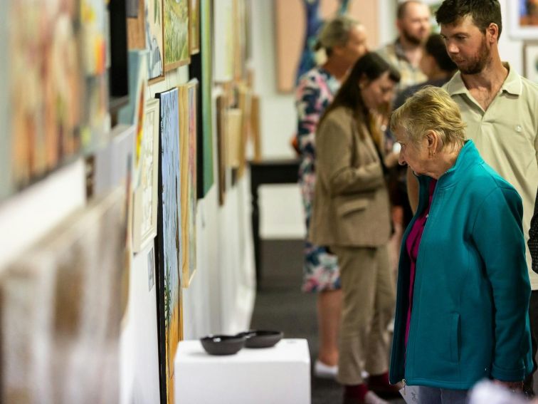 a man and a woman viewing a display of artwork on a wall inside the Art Gallery