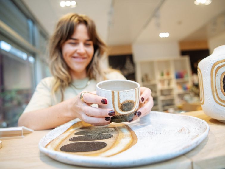 Woman picks up cup from ceramic platter