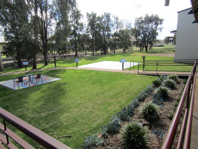 Garden area with paths, bushes and grass area with giant board games