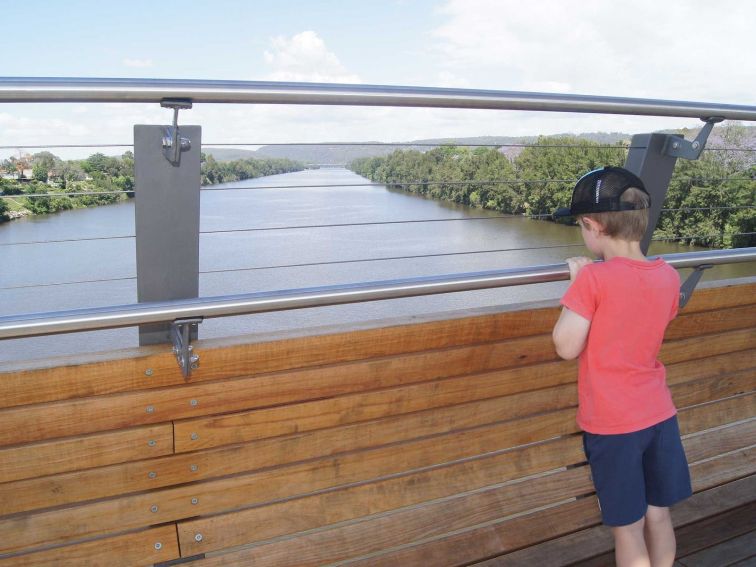 Boy looking at river from bridge