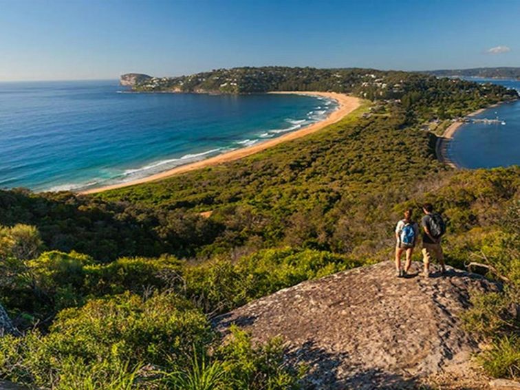 Two people walking to Barrenjoey Lighthouse, admiring coastal views over Ku-ring-gai Chase National