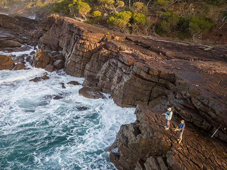 2 people fishing from the top of the rocks near Bittangabee Bay. Photo: John Spencer &copy; DPIE