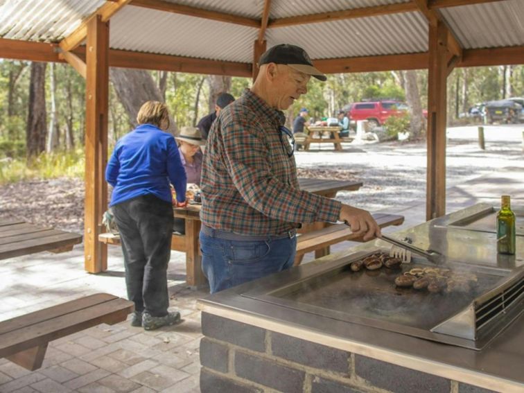 A group of people having a picnic under the shelter at Boonoo Boonoo Falls picnic area in Boonoo