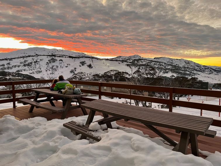 Parent and child sitting on deck enjoying the sunset at Perisher Valley