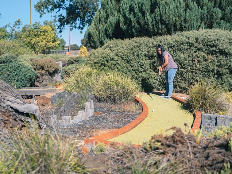 Young lady playing mini golf