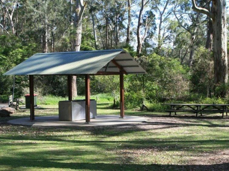 A barbecue shelter with picnic tables nearby at Carter Creek picnic area in Lane Cove National Park.