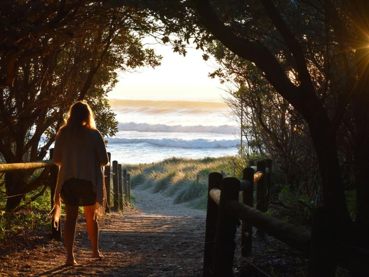 Lady walking down through bush to beach