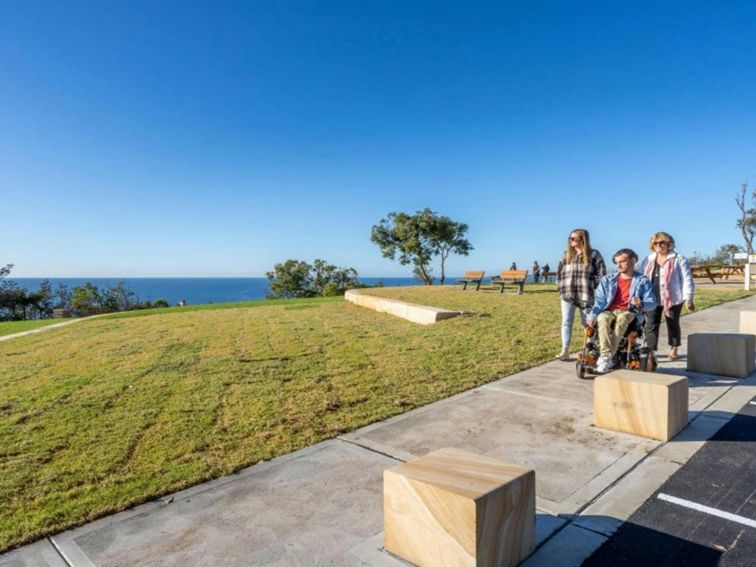 A group of friends on the concrete path at Crackneck Point lookout in Wyrrabalong National Park.