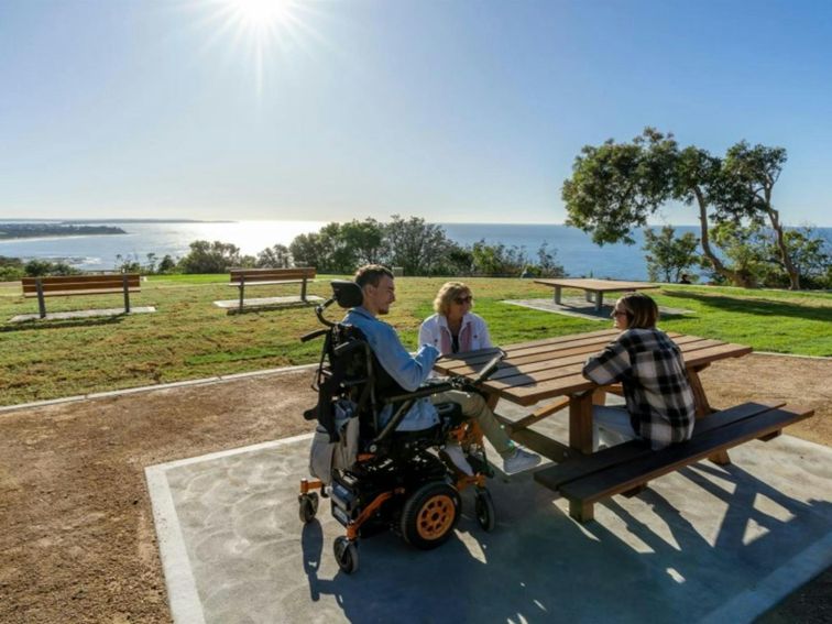 A group of friends at one of the accessible picnic tables at Crackneck Point lookout in Wyrrabalong
