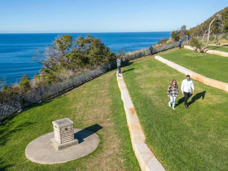 A couple walking along one of the grassy tiers at Crackneck Point lookout in Wyrrabalong National