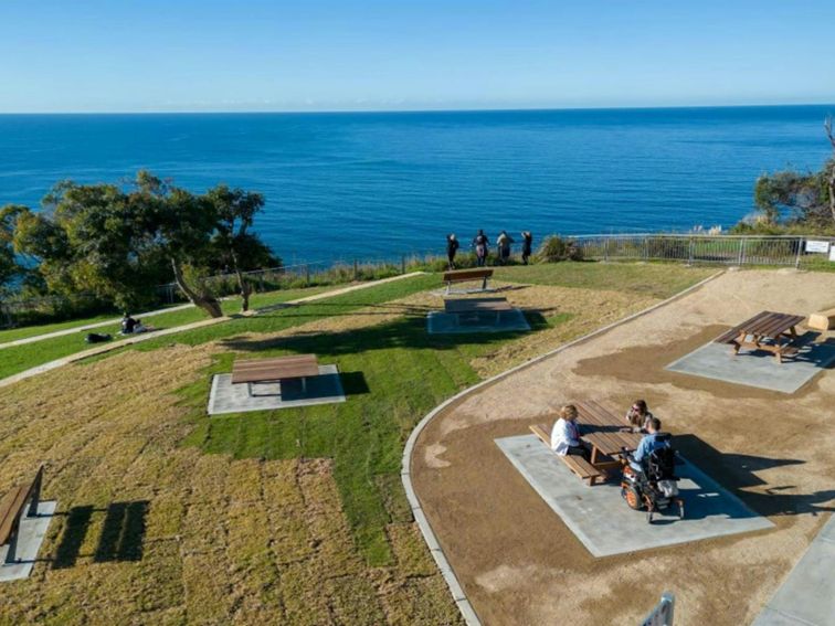 A low aerial view of Crackneck Point lookout with picnic tables and benches in Wyrrabalong National