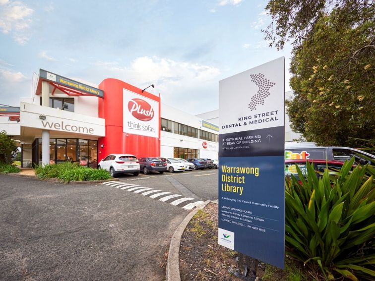 An exterior sign for Warrawong Library at the carpark entrance.