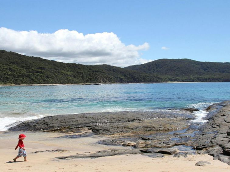 Child walking along Depot Beach in Murramarang National Park. Photo: John Yurasek/DPIE