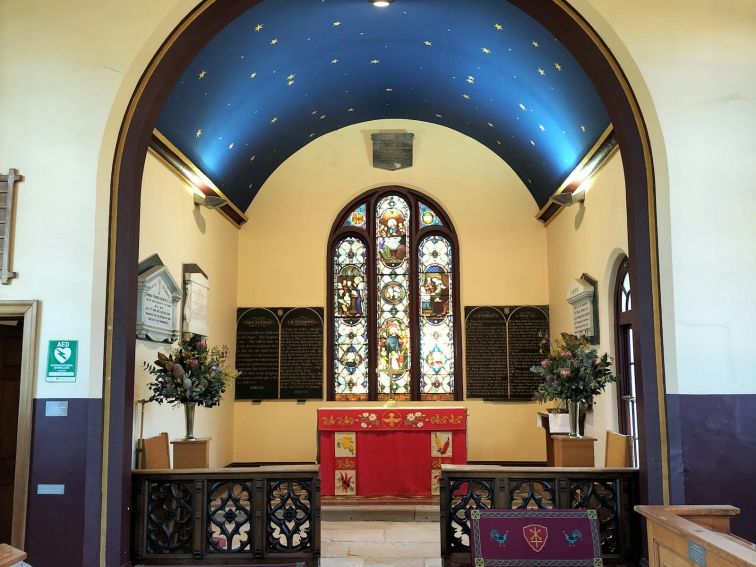 An image of the alter in St Peters Anglican church. There is a stained glass window behind