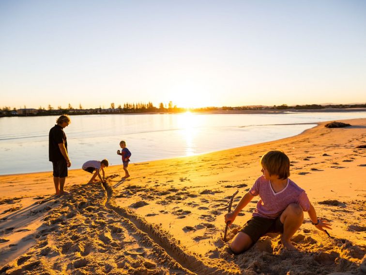 Kids playing in sand at sunset