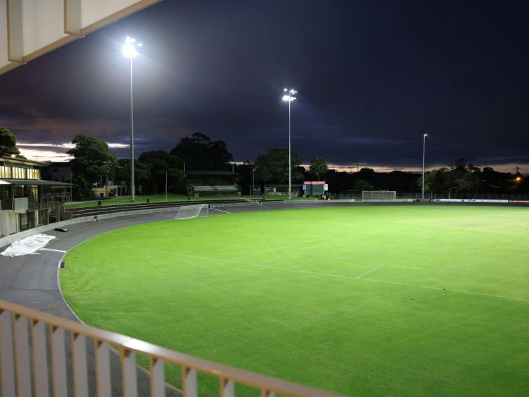 A photo of Hurstville Oval at night with the field lights lit on the field