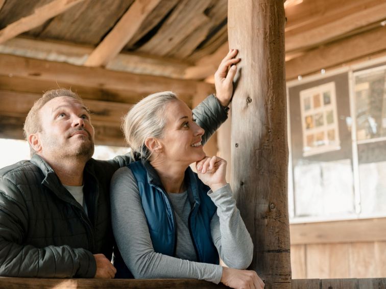 A closeup of a man and a woman standing inside a shearing shed, looking around.