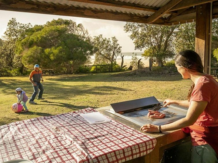 A woman cooks some sausages on the grill, Haycock Point picnic area, Beowa National Park. Photo:
