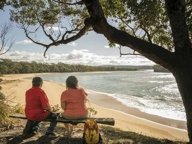 2 people sitting on a bench seat looking out the Bithry Inlet, mouth of the Wapengo Lake in Mimosa