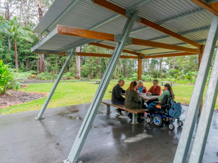 Visitors sitting at a picnic shelter at Minyon Falls picnic area in Nightcap National Park. Credit: