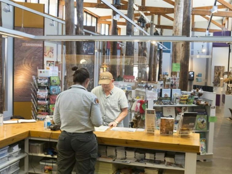 An NPWS worker gives advice to a visitor at the counter, Pilliga Forest Discovery Centre. Photo: