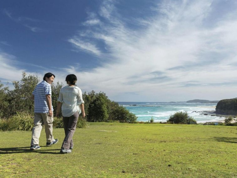 Couple walking at Pretty Beach picnic area in Murramarang National Park. Photo credit: David