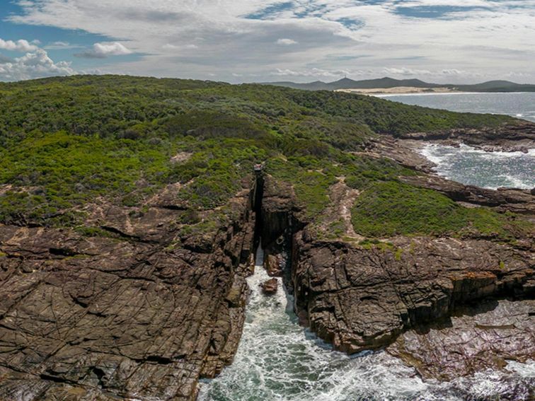 Aerial photo of Slot canyon lookout, perched over the a gap in the cliffline above the ocean.