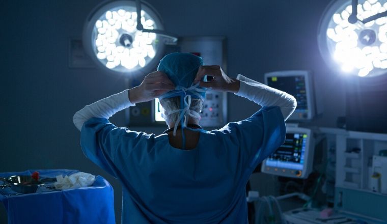 A female surgeon wearing a surgical mask in a operating room