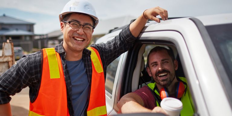 Two men smiling, one in a ute