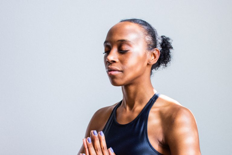 Young woman with eyes closed and hands in together in prayer