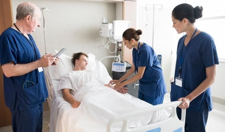 Experienced and young medical staff tending a young man in a hospital bed