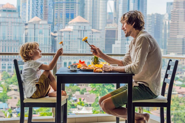 A father and son on the balcony of an apartment having a meal