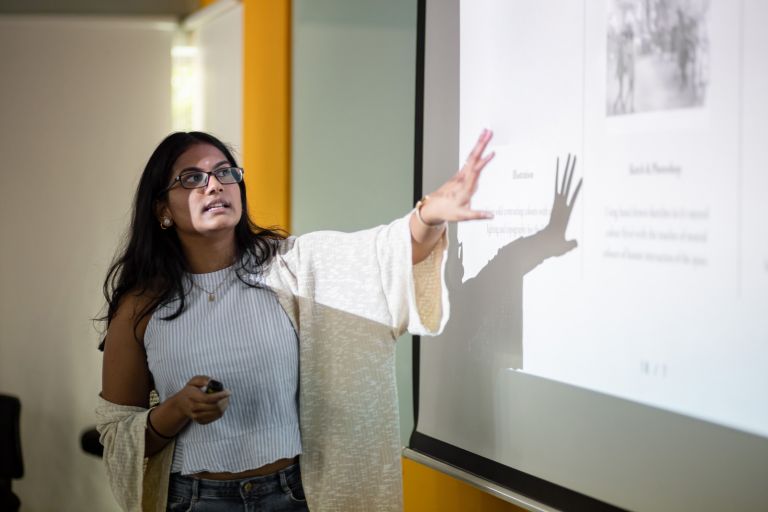 Woman teacher pointing at image and text projected onto screen