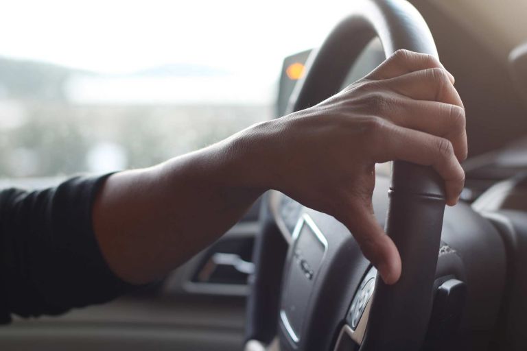 A hand on a car steering wheel