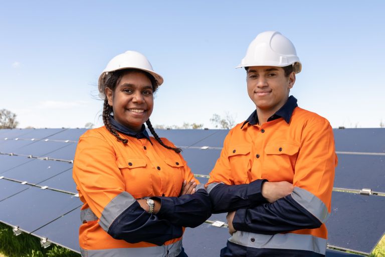 Aboriginal workers standing in front of solar panels